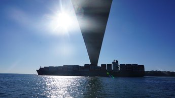 cargo ship passing beneath bridge