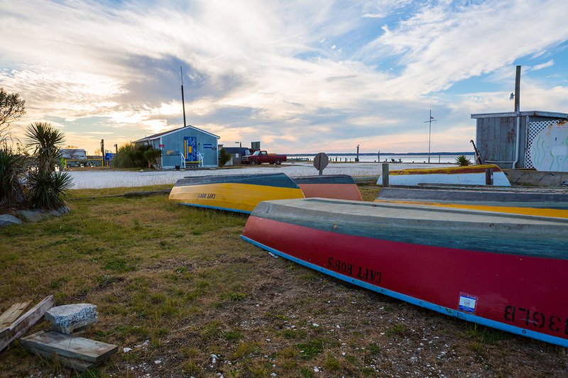 Small rental boats on the grass along a waterfront.